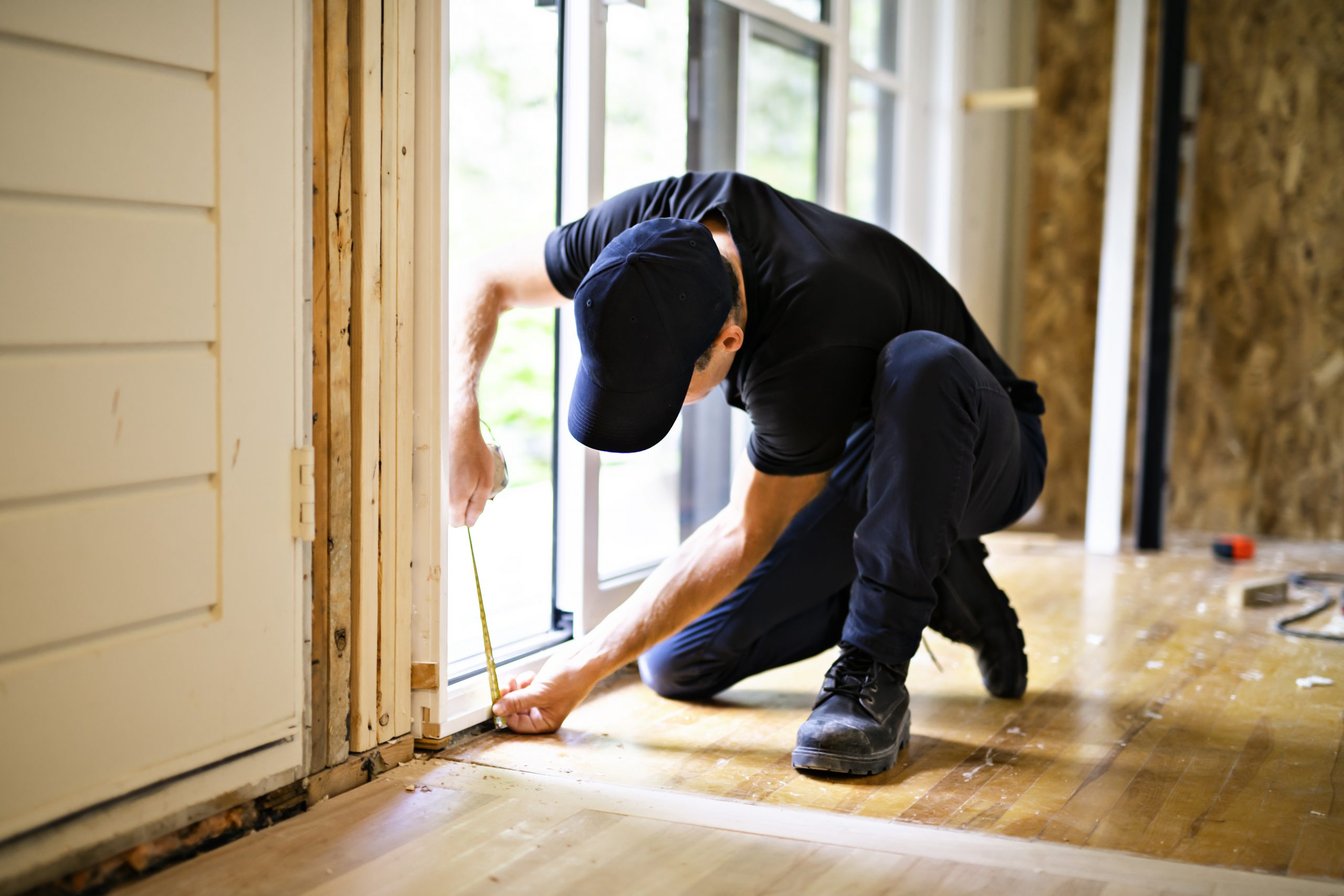 A handsome young man installing Double Sliding Patio Door in a new house construction site